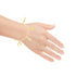 A hand adorned with the exquisite Mega Lucky Charm Anklet Bracelet glimmers gracefully. This chic accessory, crafted from 14k gold-filled material, boasts charms such as a figa hand, horseshoe, money bag, clover, and lucky chili—each representing spiritual protection. Set against a plain white background, it captures both style and significance.